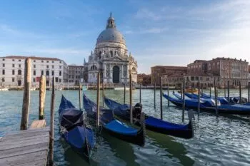 Church with dome on water with gondolas in foreground